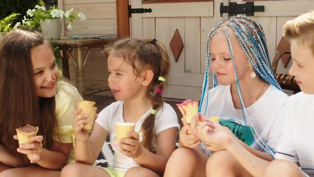 Concept of delicious food and children's happy emotions. Smiling multiethnic children eating ice cream and having fun together on family summer vacation on the summer terrace.