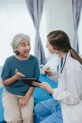 Beautiful modern female doctor talking to an elderly woman patient with a smiling face at the hospital.