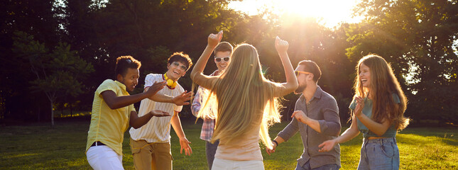 Carefree, cheerful young people having fun at an outdoor summer party. Diverse group of happy good...