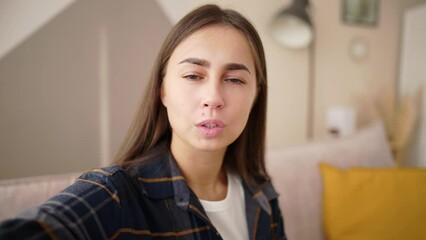 Young woman blogger talks with subscribers shooting selfie video and smiles holds camera in one hand. She emotionally explains something. Blogging, online work, job, communication with people in vlog. - Powered by Adobe