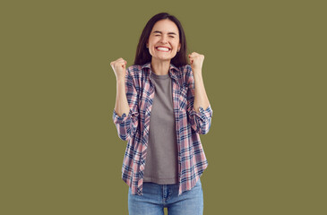 Happy overjoyed young woman clenching her fists feeling happy. Portrait of excited girl wearing casual clothes expressing positive emotions, celebrating success or goal achievement