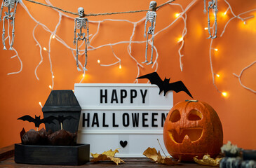 Happy Halloween white sign with black letters, pumpkin and halloween decoration.