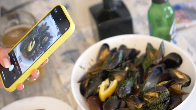 Woman taking pictures of food through her smartphone and watching gallery