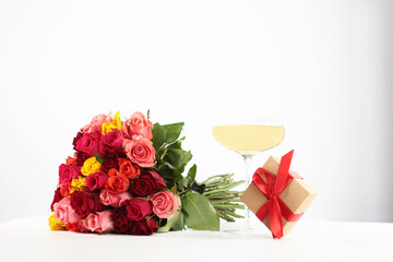 A large bouquet of roses on a white background. A gift in a box. A glass of champagne with roses. White background. The concept of the holiday.Birthday.Copy space.