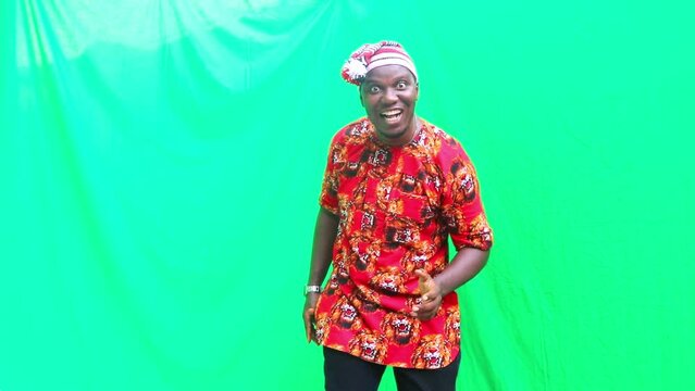 Igbo business man in 3D marketing presentation of imaginary products falling from the sky and happy dancing in front of green screen that can be digitally removed