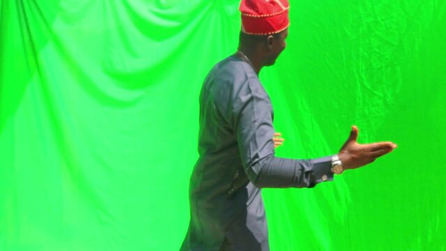 Dancing African Yoruba man in blue dress and orange cap