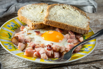 Fried eggs with ham on an old wooden background.
