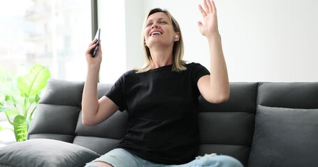 Young beautiful woman in wireless headphones listening to music and dancing at home. Blogger girl broadcasts good mood live