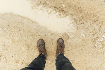 Fototapeta premium View from above on pair of trekking shoes in a mud, Hiking boots stuck in mud