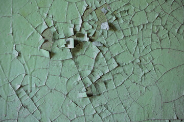 Old dry surface in the cracks. Piece of the pattern, a background or wallpaper for your desktop. Cracked green paint on surface. Peeling paint rough texture.