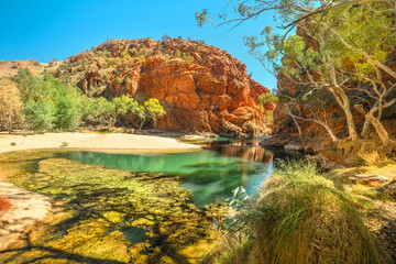 Panoramic view of Ellery Creek Big Hole waterhole in West MacDonnell Ranges surrounded by red cliffs and bush outback vegetation. Northern Territory, Central Australia.
