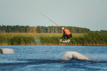 Wake boarding female sportsman girl jumping high wake boarding raley trick with huge water splash...