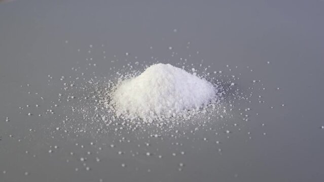 Aspartame powder is poured in slide on grey surface. Sugar substitute, artificial sweetener. Chemical formula	C14H18N2O5. Food additive E951 used as sugar substitute in foods and beverages.