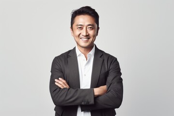 Portrait of a smiling asian businessman with arms crossed over white background