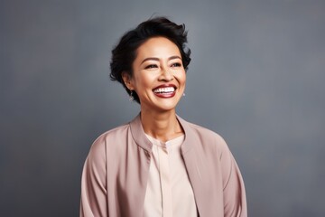 Fototapeta premium Portrait photography of a happy Indonesian woman in her 40s wearing a chic cardigan against an abstract background 