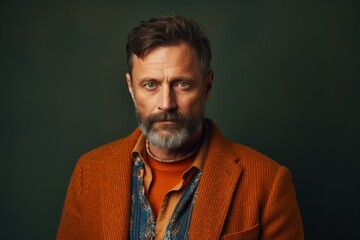 Portrait of a handsome mature man with grey beard and mustache in an orange jacket.