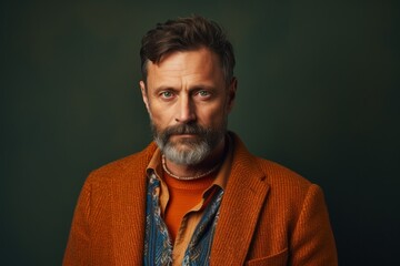 Fototapeta premium Portrait of a handsome mature man with grey beard and mustache in an orange jacket.