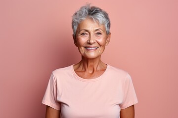 Portrait of smiling senior woman looking at camera isolated on pink background