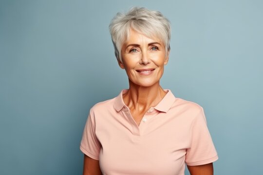 smiling senior woman looking at camera on blue background with copy space