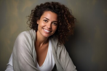 Fototapeta premium Portrait of a beautiful young woman with curly hair smiling and looking at the camera