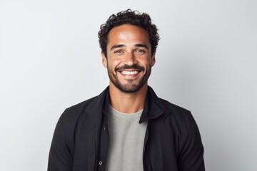 Portrait of handsome man with curly hair smiling at camera while standing against white background