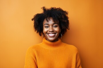 Obraz na płótnie Canvas Portrait of a beautiful young african american woman smiling against orange background