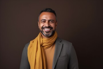 Obraz premium Portrait of a smiling Indian man wearing a yellow scarf on brown background