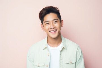Portrait of a happy young asian man smiling on pink background
