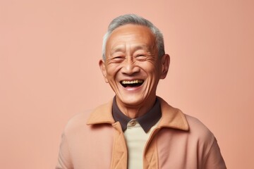 Fototapeta premium Portrait of an old asian man laughing on a pink background