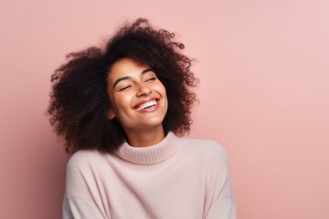Portrait of a beautiful african american woman with curly hair smiling against pink background