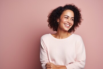Cheerful young woman looking at camera and smiling while standing against pink background