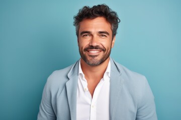 Portrait of handsome young man looking at camera and smiling while standing against blue background
