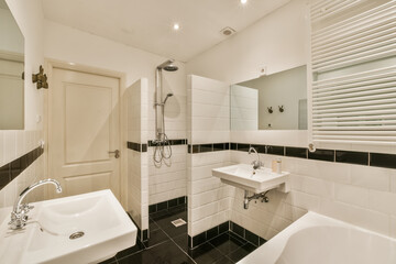 a modern bathroom with black and white tiles on the walls, sink, mirror, and shower stall in it