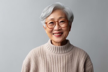 Portrait of senior Asian woman wearing eyeglasses on grey background