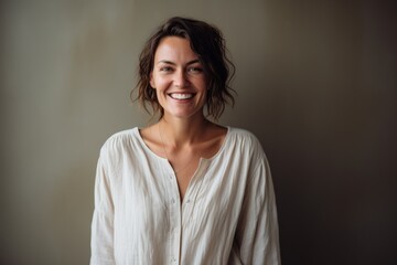 Portrait of a smiling young woman standing against grey wall at home