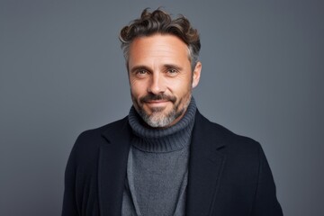 Obraz premium Portrait of handsome mature man in sweater looking at camera and smiling while standing against grey background