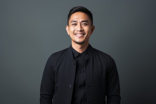 Portrait of happy asian man in black shirt on grey background