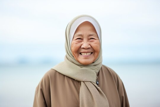 Happy Asian Muslim Senior Woman Wearing Hijab On The Beach.