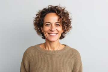 Portrait of a smiling woman with curly hair looking at camera over gray background
