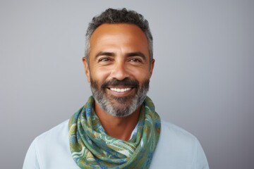 Portrait of a smiling Indian man with a scarf over grey background