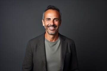 Obraz premium Portrait of handsome mature man smiling at the camera against grey background