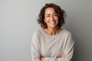Portrait photography of a happy Brazilian woman in her 50s wearing a cozy sweater against a minimalist or empty room background 