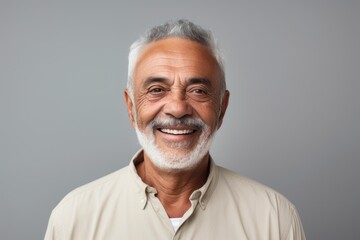 Portrait of a smiling mature man looking at camera over grey background