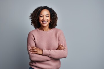 Obraz premium Portrait of a smiling african american woman standing with arms crossed against grey background