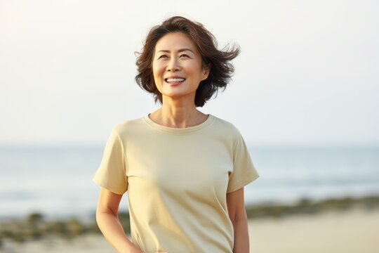 happy asian woman in yellow t-shirt standing on the beach