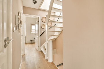 a hallway in a house with white walls and wood flooring, there is a staircase leading up to the second floor