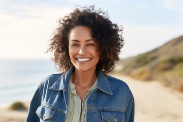 Close up portrait of a smiling young woman with curly hair at the beach