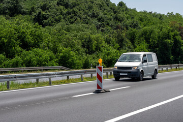 White modern delivery small shipment cargo courier van moving fast on motorway road to city urban suburb.	