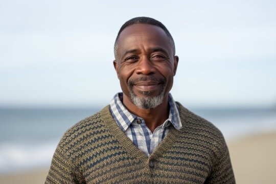 Portrait photography of a satisfied Nigerian black man in his 50s wearing a chic cardigan against a beach background 