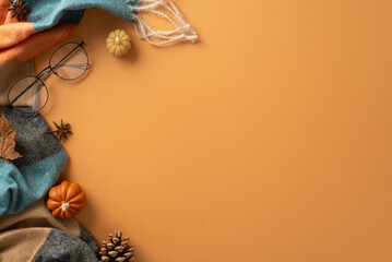 Above view of a warm and cozy autumn ambiance at home. Glasses, patchy scarf, pumpkin candles, maple foliage and aromatic chinese anise create a perfect brown backdrop for text or advert placement